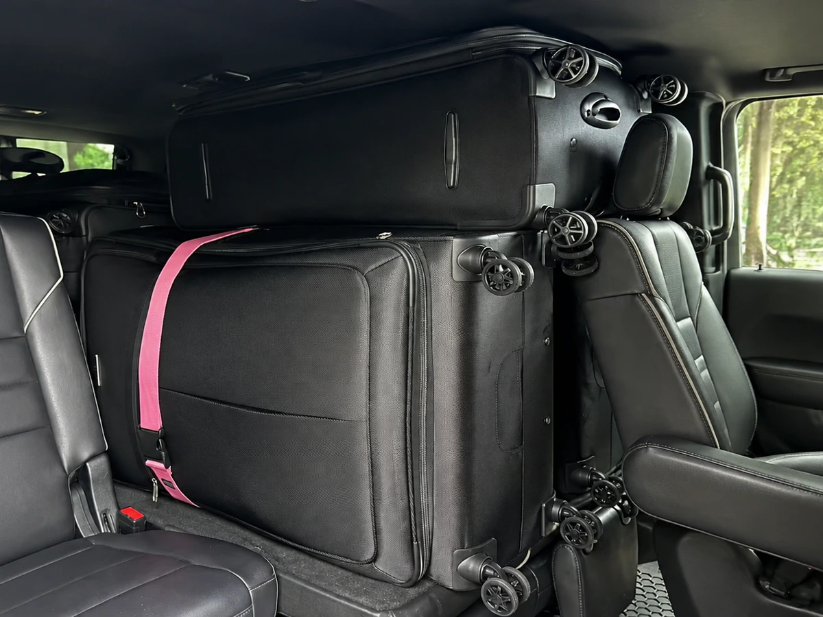 Full-size black SUV interior carrying several large black suitcases for an airport trip