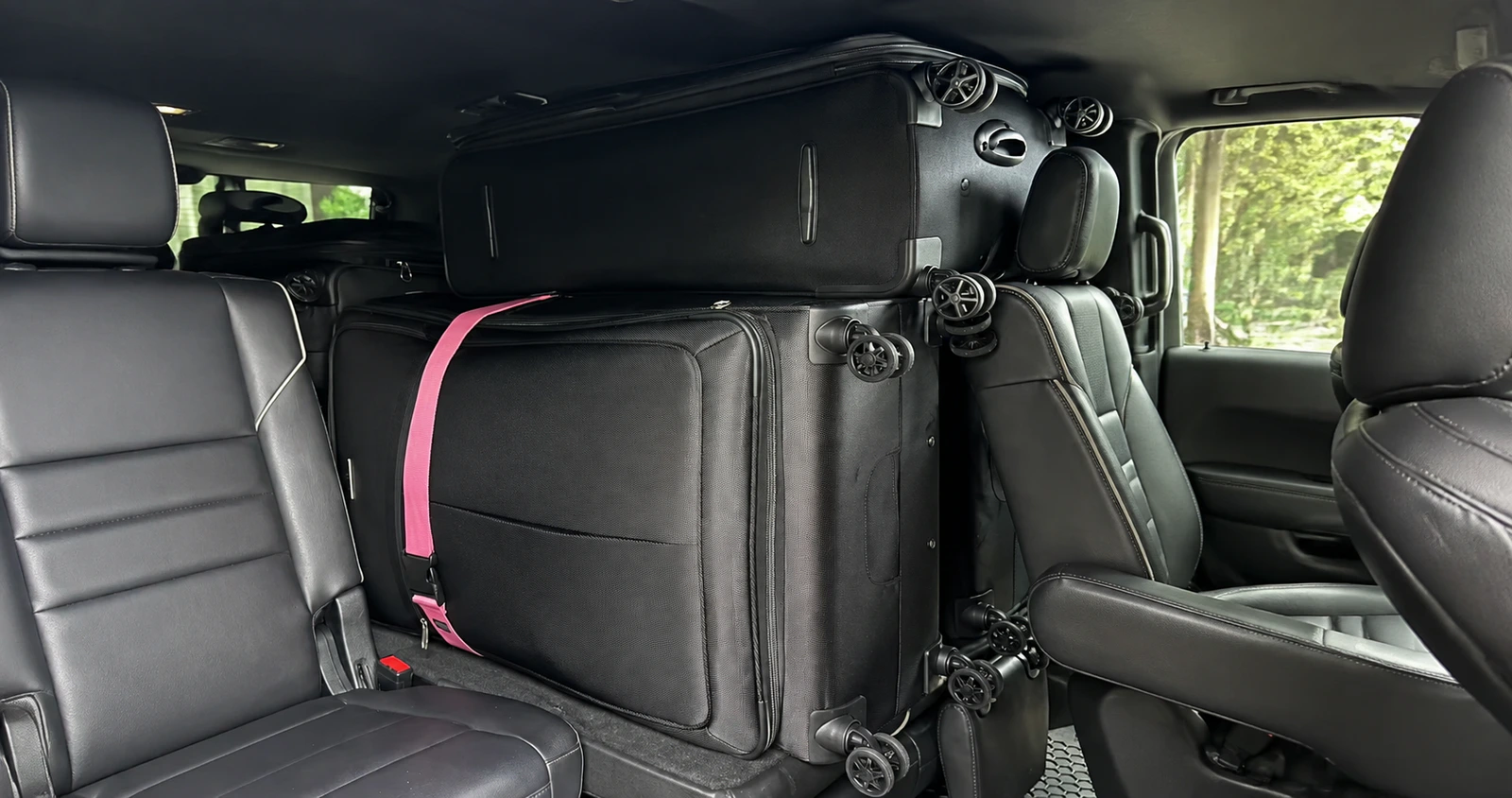 Large suitcases arranged inside a full-size SUV cabin for an airport family transfer